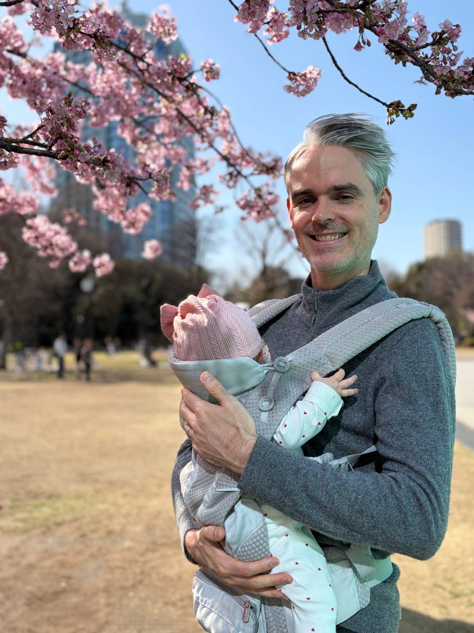 Jason Kobayashi holding his baby daughter under cherry blossoms in Tokyo.